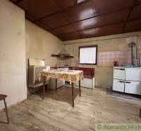 Kuchyně v rodinném domě s podlahou s dřevěným dekorem a jednoduchým vybavením.