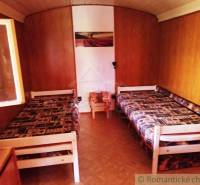 Dřevěný interiér chaty s dvěma lůžky a podlahou s dřevěným dekorem.