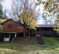 Chata v Dudincích obklopená stromy a svěží zelení, ideální na odpočinek.