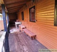 Chata v Dudincích s verandou s podlahou s dřevěným dekorem a lavičkou.