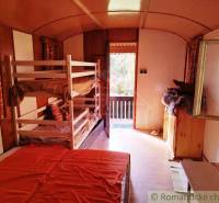 Interiér chaty se čtyřmi postelemi a prosvětleným výhledem na terasu.