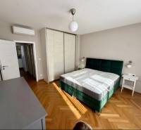 Ložnice s postelí, skříní a podlahou s dřevěným dekorem ve 3-pokojovém bytě.