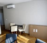 Jídelní kout se stolem, židlemi a podlahou s dřevěným dekorem ve 3-pokojovém bytě.