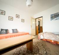 Obývací pokoj v rodinném domě s kobercem a kresbami na stěně.