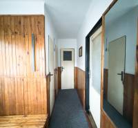 Vstupní chodba v rodinném domě s dřevěným obkladem a zrcadlem na stěně.