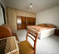 Ložnice v rodinném domě s kobercem, postelí a skříní.