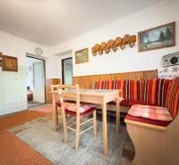 Jídelna rodinného domu s rohovou lavicí, dřevěným dekorem a dekorativními obrázky na stěně.