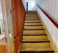 Dřevěné schodiště s dřevěným zábradlím a stěnou v interiéru chaty.