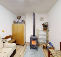 Pokoj v chatě s pecí, pohovkami a dekoracemi, podlaha s dřevěným dekorem.