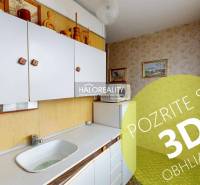 Kuchyně ve 3-pokojovém bytě s bílými skříňkami a obrázky na stěnách.