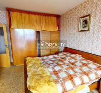 Ložnice ve 3pokojovém bytě s dekorační tapetou a dřevěným nábytkem.