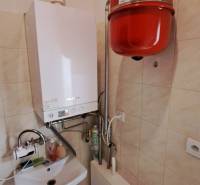 Plynový kotel s umyvadlem v obchodních prostorách, dlažba, stěny obložené dlaždicemi.