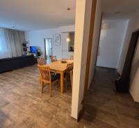 Jídelní stůl s dřevěnými židlemi v 2-pokojovém bytě. Součástí je pohovka a televizor.