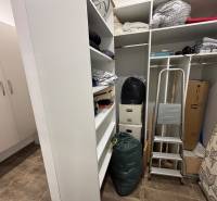 Úložný prostor v 2-pokojovém bytě s regály, schůdky a krabicemi.