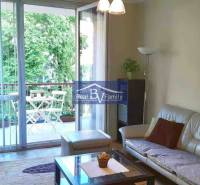 Obývací pokoj v 2pokojovém bytě s prostorným balkonem a výhledem na zeleň.