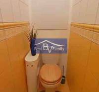 Toaleta s béžovými stěnami a kachličkami v 2-pokojovém bytě s dekorací.