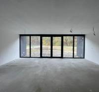 Prostorná místnost s velkými okny v rodinném domě, výhled do zahrady.