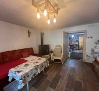 Pohodlný pokoj v chatě s útulným posezením, krbem a dřevěným stropem.