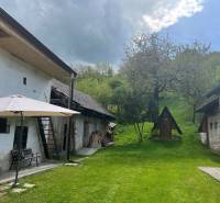 Dvorek starší chaty s altánkem na lavičce, zahrada v přírodním prostředí na kopci.