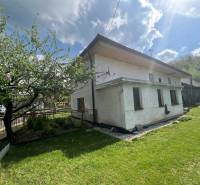 Chata v Šípkově obklopená zelení, oplocená zahrada se stromy a loukou.