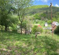 Krásná přírodní scenérie s chatou, stromy a malebnou vesničkou na pozadí kotliny.