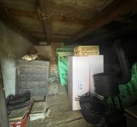 Skladovací prostor na chatě v Šípkově s dekorativní pecí a různými boxy.