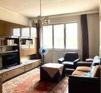 Obývací pokoj v 3pokojovém bytě s nábytkem, koberec a velké okno.