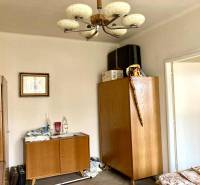 Pokoj v 3-pokojovém bytě s dřevěným nábytkem a dekorativním lustrem.