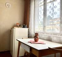 Jídelna ve 3-pokojovém bytě se stolem, židlemi a záclonami s květinovým vzorem.