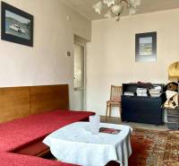 Obývací pokoj v 3pokojovém bytě s pohovkou, kobercem a dekorativními obrázky na stěně.