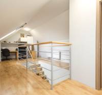 Podkrovní pracovna ve 4pokojovém bytě s dřevěným dekorem podlahy a zábradlím.