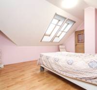 Světlá ložnice s dvojitými střešními okny a podlahou s dřevěným dekorem ve 4pokojovém bytě.