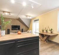 Interiér 4-pokojového bytu s podlahou s dřevěným dekorem, dřevěnými prvky a rostlinami.