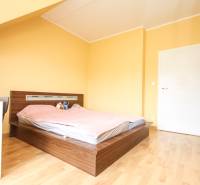 Ložnice ve 4pokojovém bytě s postelí a podlahou s dřevěným dekorem.