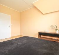 Ložnice ve čtyřpokojovém bytě s podlahou s dřevěným dekorem.