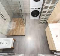 Koupelna s pračkou a sprchovým koutem ve 4-pokojovém bytě, podlaha s dřevěným dekorem.