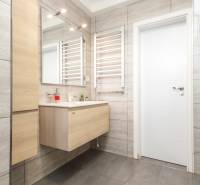 Koupelna s umyvadlem, zrcadlem a světlými obklady ve 4pokojovém bytě.