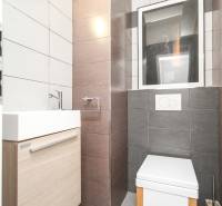 Koupelna ve 4-pokojovém bytě se světlými obklady, umyvadlem a toaletou.