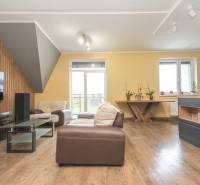 Obývací pokoj čtyřpokojového bytu s podlahou s dřevěným dekorem, pohodlné sezení a světlo.