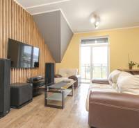 Obývací pokoj s pohovkou, televizorem a podlahou s dřevěným dekorem ve 4pokojovém bytě.