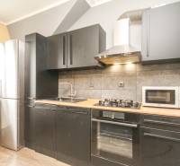 Kuchyně ve 4-pokojovém bytě s černými skříňkami a podlahou s dřevěným dekorem.