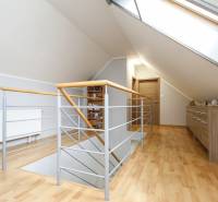 Podkrovní chodba ve 4pokojovém bytě s podlahou s dřevěným dekorem a střešním oknem.