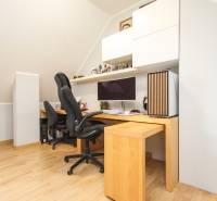 Domácí kancelář ve 4-pokojovém bytě se stolem, židlí a podlahou s dřevěným dekorem.