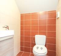 Koupelna ve 4-pokojovém bytě s dlažbou a kompaktním sanitárním zařízením.