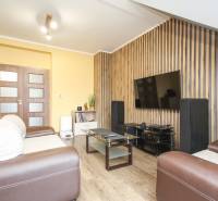 Obývací pokoj ve 4pokojovém bytě s TV, pohovkou a podlahou s dřevěným dekorem.