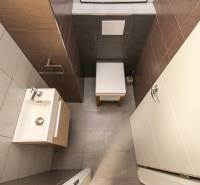 Koupelna ve 4-pokojovém bytě s umyvadlem, barevné dlaždice a kompaktní design.