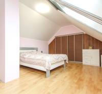 Ložnice ve 4pokojovém bytě s podlahou s dřevěným dekorem a střešním oknem.