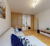 Obývací pokoj v jednopokojovém bytě s podlahou s dřevěným dekorem a sedací soupravou.