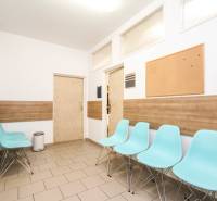 Čekárna s modrými židlemi, korkovou nástěnkou a podlahou s dřevěným dekorem v kanceláři.