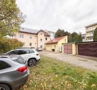 Parkoviště u kanceláří na Bratislavské ulici v Žilině, auta a garáže v pozadí.